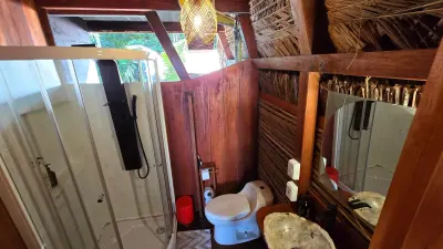 Baño de la cabaña VIP con ducha, inodoro y lavamanos de piedra.