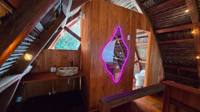 Lavamanos de piedra con espejo de borde neón violeta.