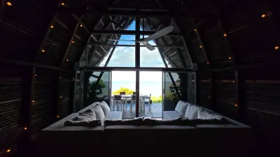 Sala con sofás blancos frente a un gran ventanal con vista al mar.