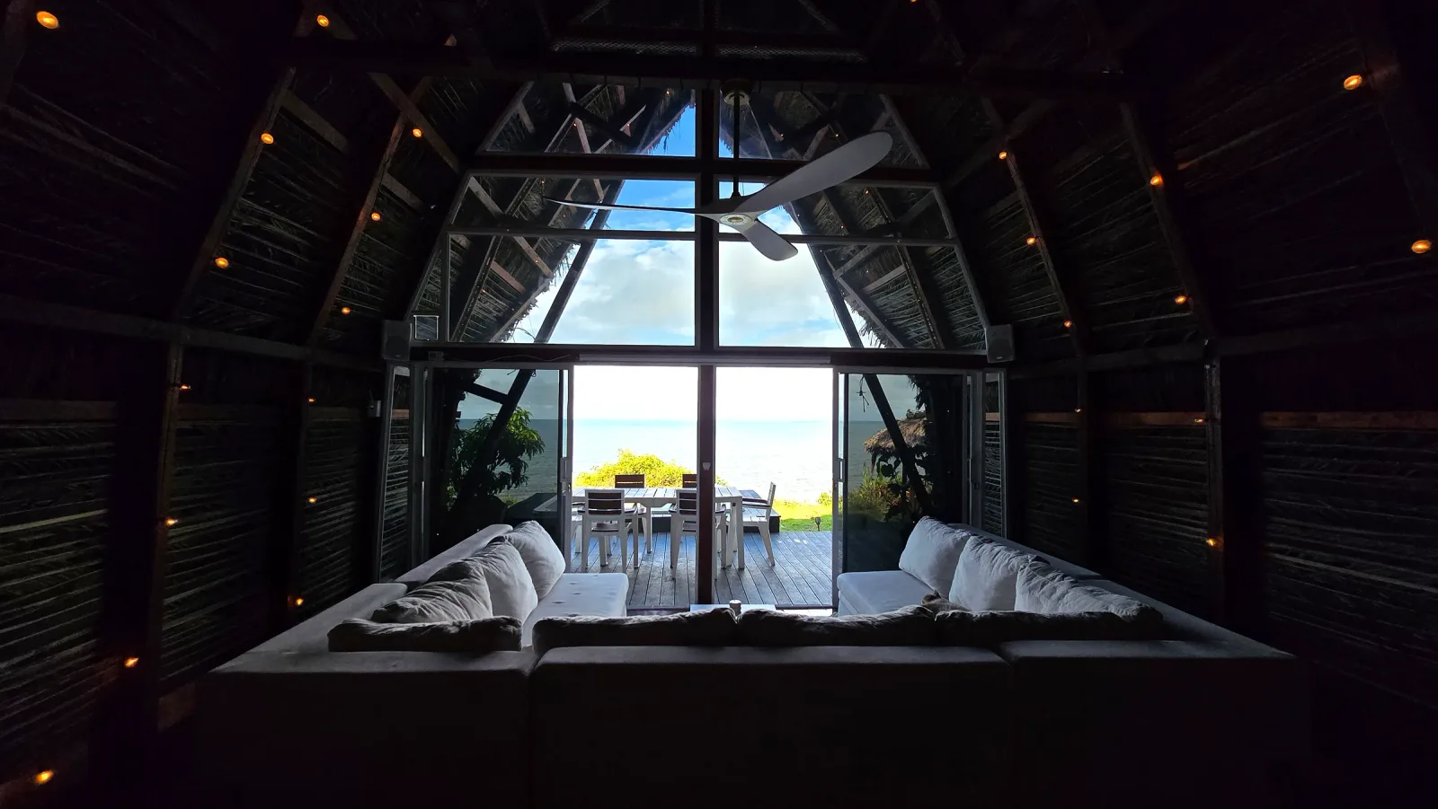 Sala con sofás blancos frente a un gran ventanal con vista al mar.