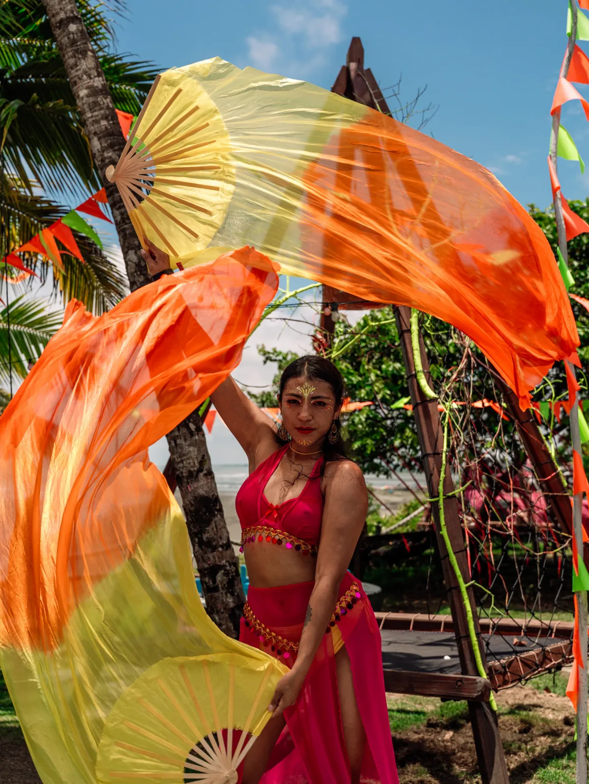 Artista con grandes abanicos durante un espectáculo tropical de fuego.