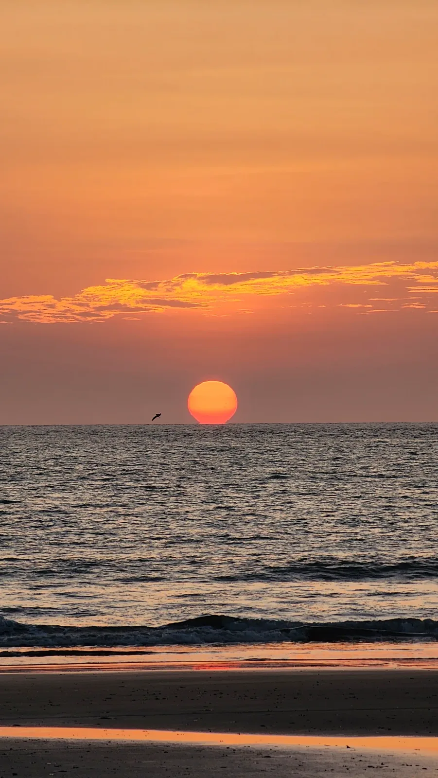 Sol anaranjado descendiendo sobre el mar al atardecer.
