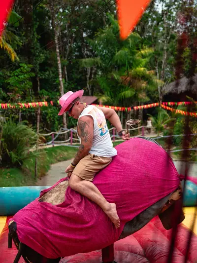 Visitante disfrutando una atracción mecánica rosa durante un evento.