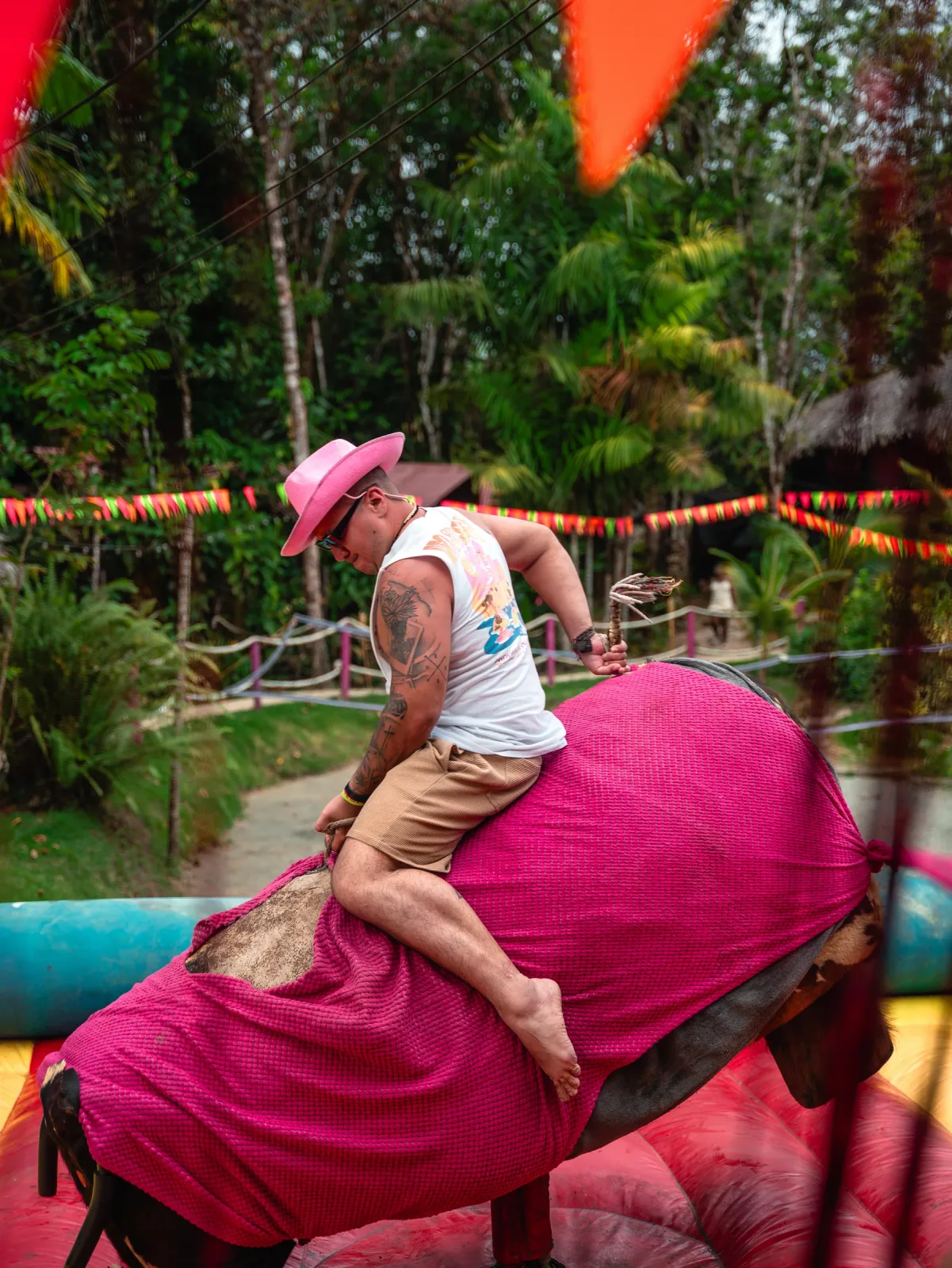 Visitante disfrutando una atracción mecánica rosa durante un evento.