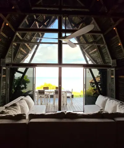 Cama dentro de una suite con gran ventanal triangular y vista exterior.