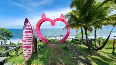 Columpio con forma de corazón, hamacas y palmeras frente al océano.