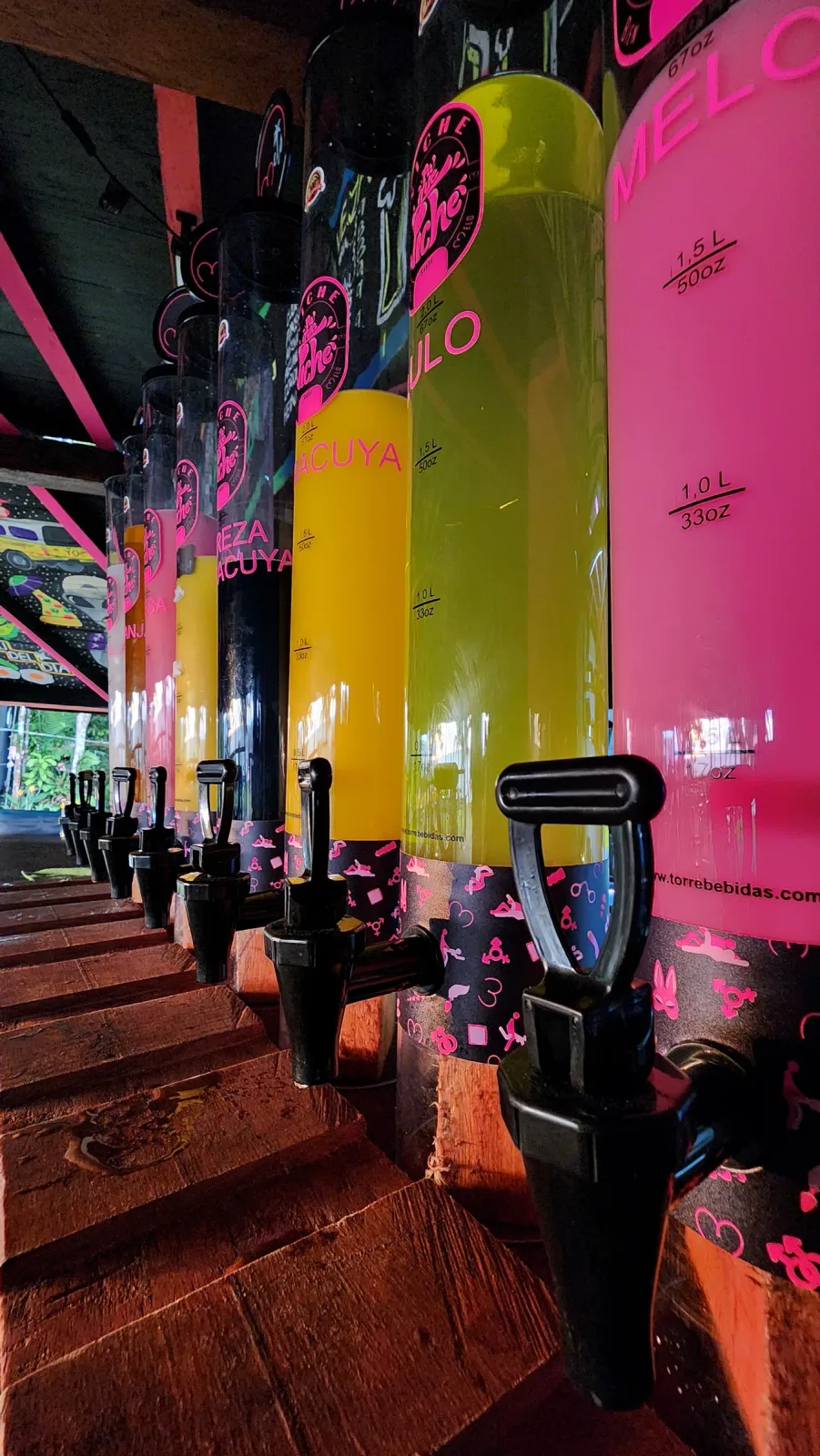 Fila de dispensadores de bebidas de colores en el bar.