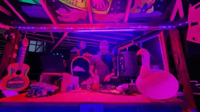 Dos DJs en una cabina iluminada en rosa durante la fiesta.