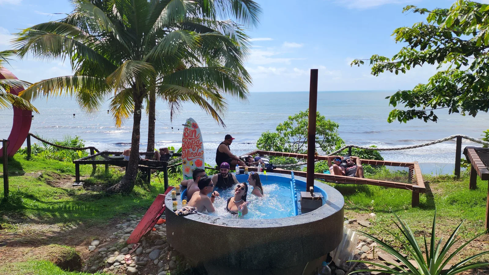 Grupo de amigos compartiendo en una piscina con vista al mar.