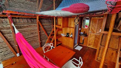 Interior de madera con hamaca rosa, baño privado y zona de almacenamiento.