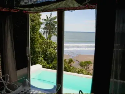 Habitación abierta hacia una piscina privada y la playa.