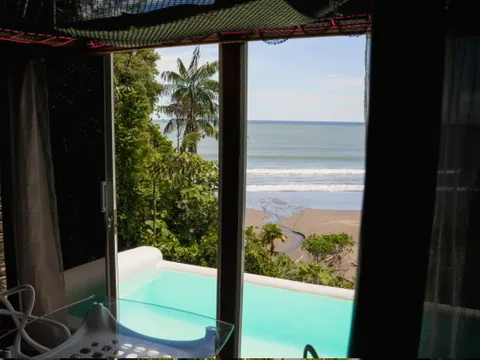 Habitación abierta hacia una piscina privada y la playa.