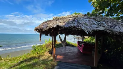 Kiosco de descanso con techo de palma y vista al océano.