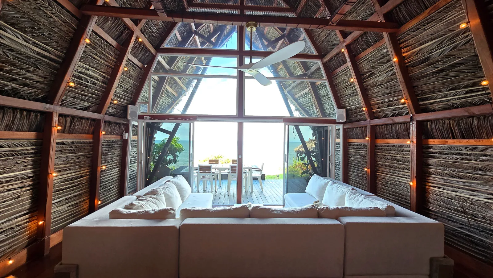 Sala luminosa con sofás blancos y acceso a la terraza frente al océano.