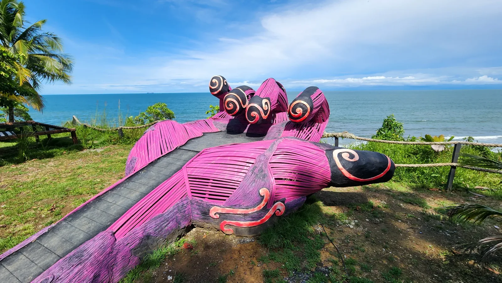 Instalación artística rosa sobre el césped de un mirador frente al mar.