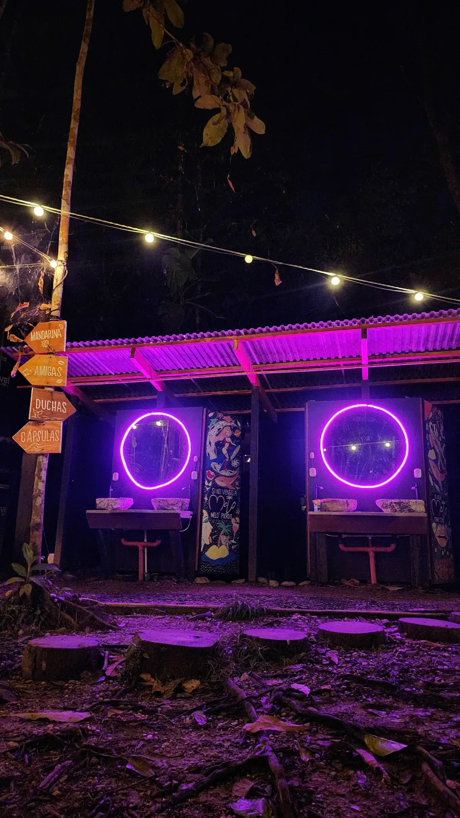 Instalación artística circular iluminada con neón rosa en la noche.