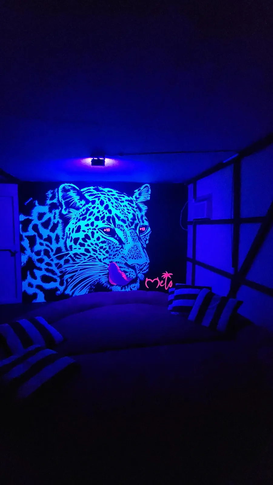 Mural de un felino iluminado con luz ultravioleta azul.