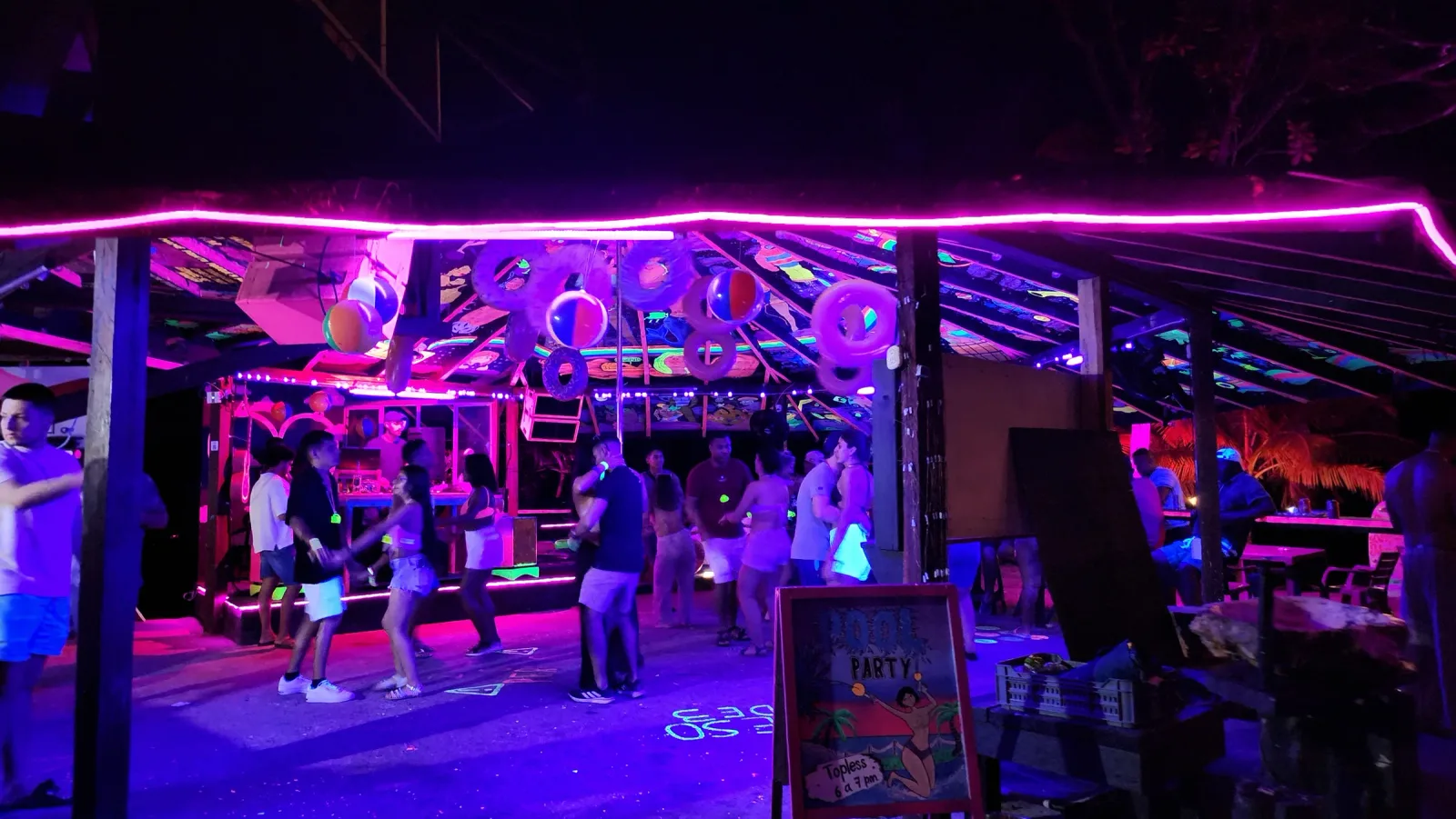 Personas bailando en una pista cubierta por arte fluorescente y luces neón.