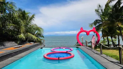 Piscina y columpio rosa con forma de corazón frente al mar.
