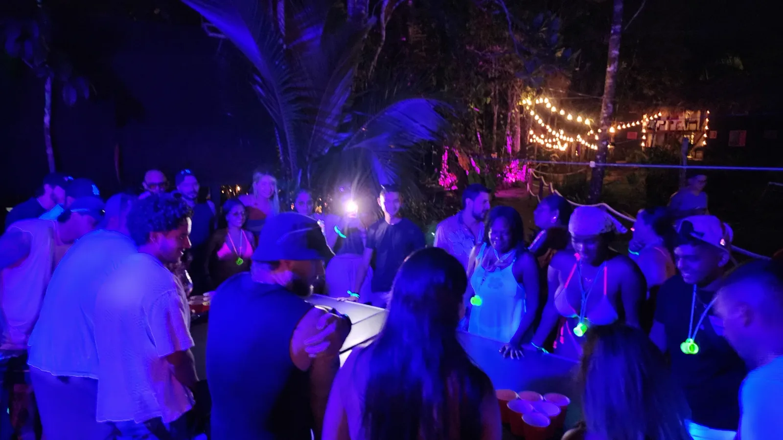 Público reunido en una fiesta bajo luces azules y violetas.