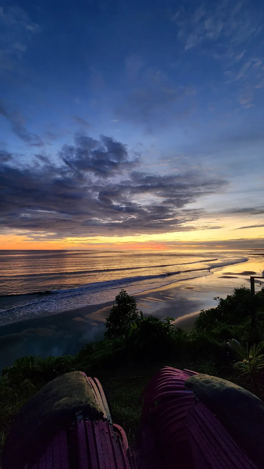 Vista amplia del litoral, las olas y el cielo azul durante el atardecer.