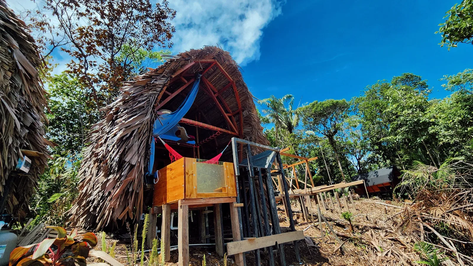 Fachada de Metemelo con balcón elevado y techo de palma.