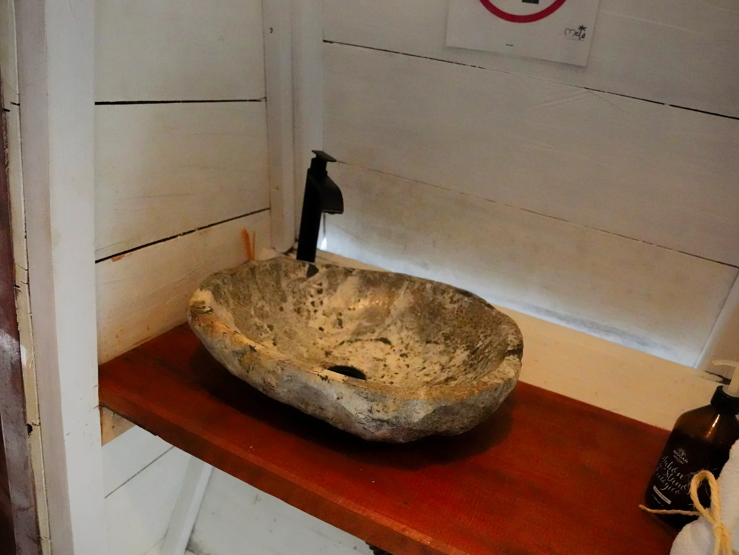Lavamanos de piedra sobre repisa de madera en el baño de la habitación Mandarina.