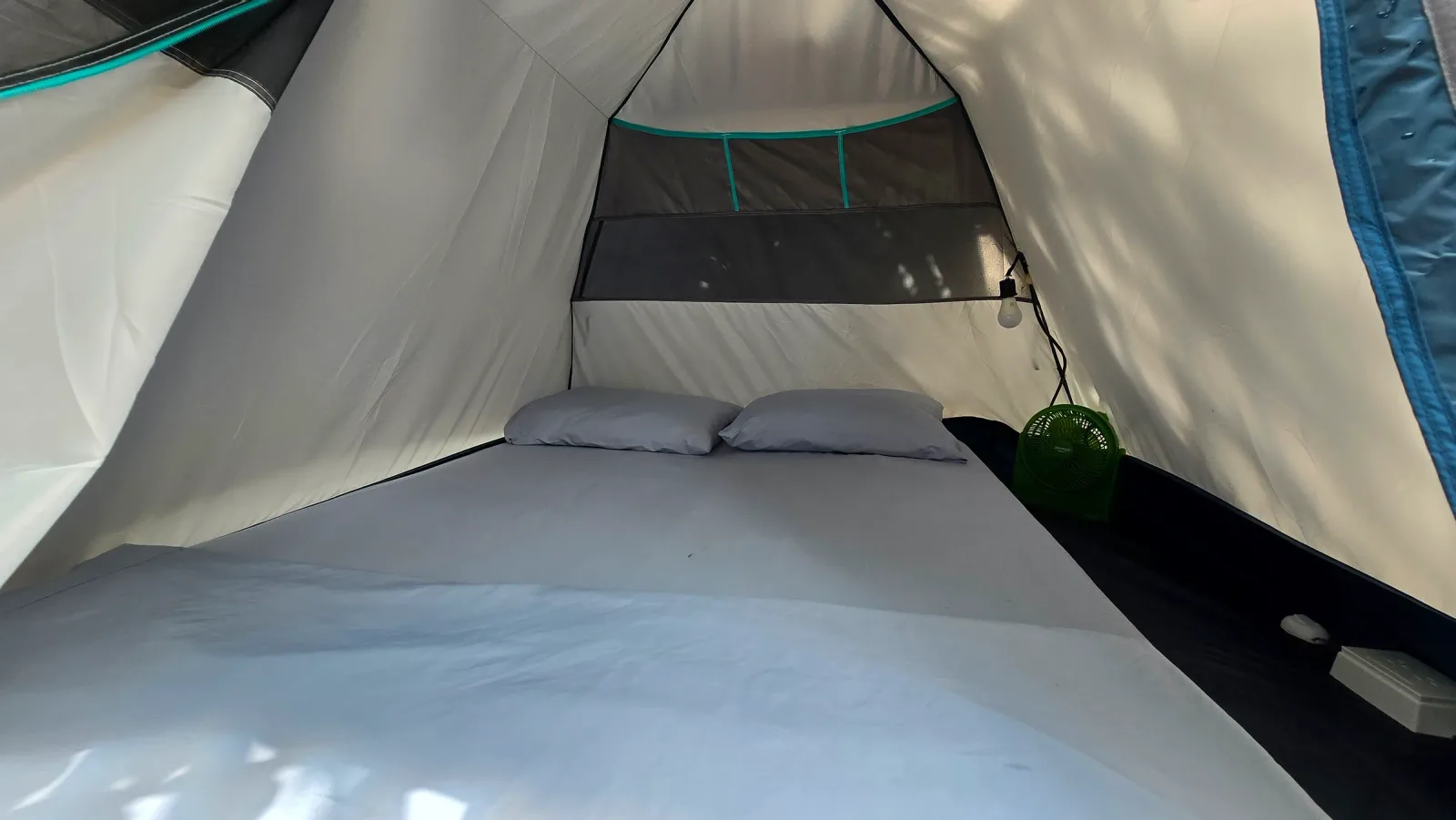 Vista frontal de la cama doble dentro de una carpa iluminada por el día.