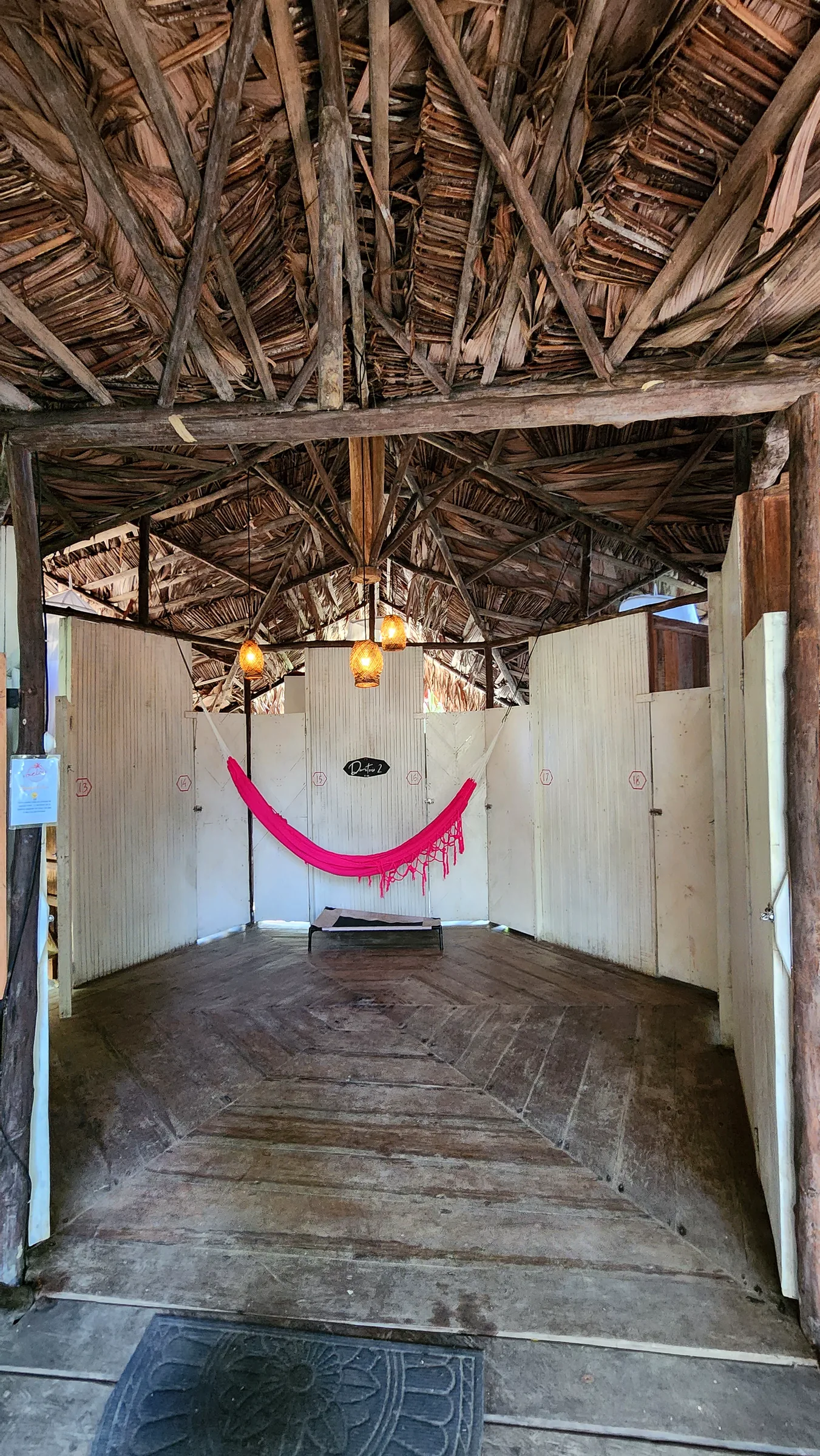 Pasillo rústico de acceso a los dormitorios cápsula bajo techo de palma.